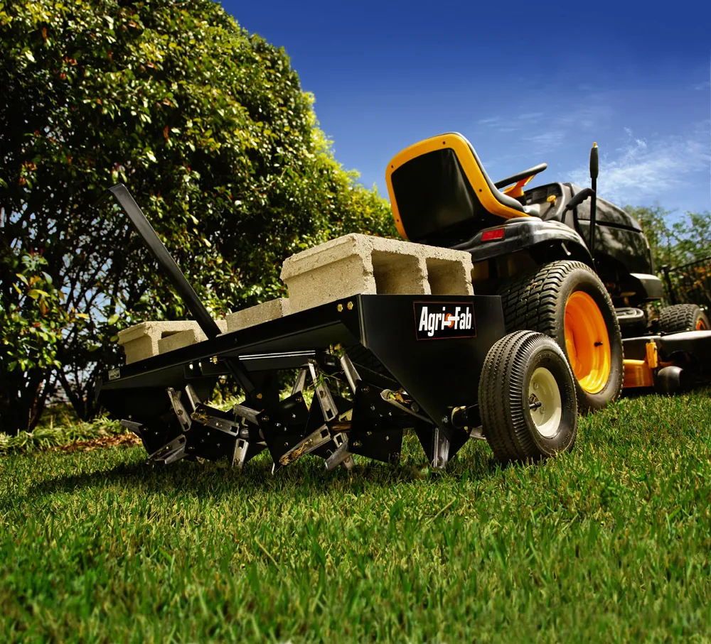 Tow-behind core plug aerator with hollow tines on a green lawn