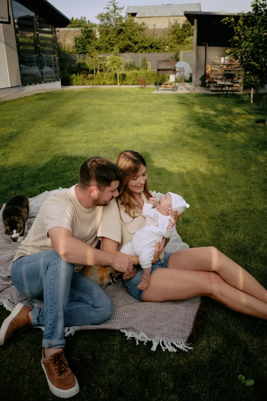 Family relaxing on a picnic blanket on the grass in a sunny backyard