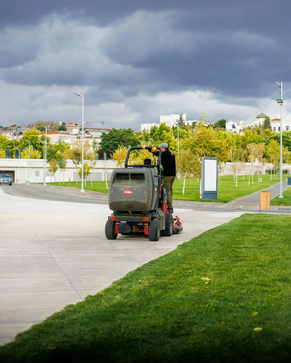 Park-maintenance worker operating a ride-on lawn mower
